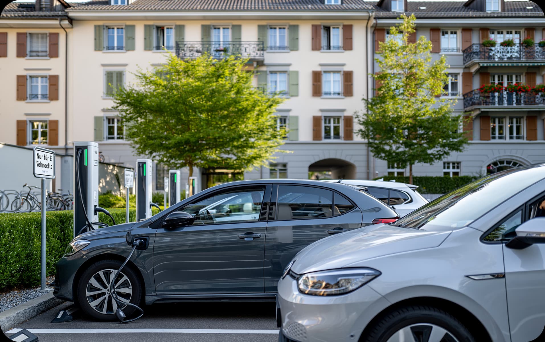 Elektrofahrzeuge an Ladestationen vor einem Wohnhaus
