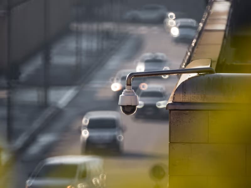 Surveillance camera on a building corner above a busy road