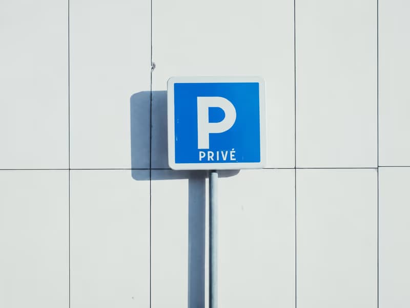 Blue ‘P privé’ private parking sign on a white facade