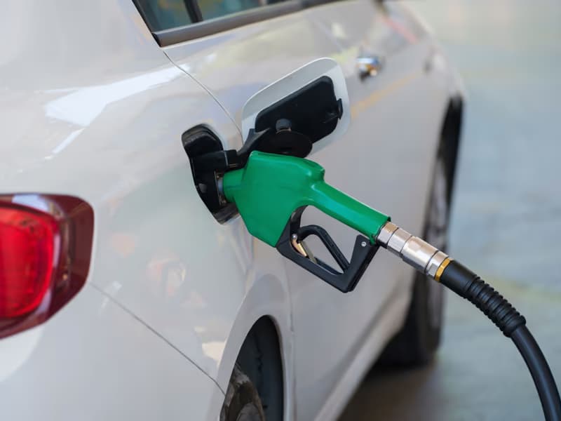 Green fuel nozzle in the filler neck of a white car