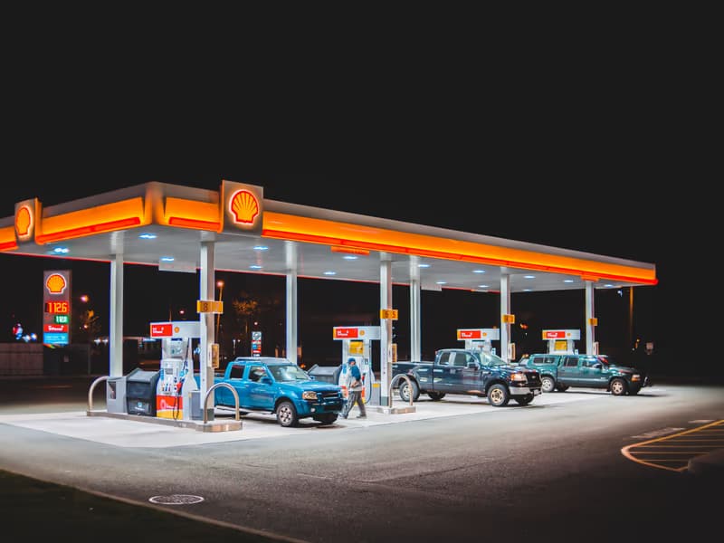 Brightly lit petrol station at night with vehicles at the pumps