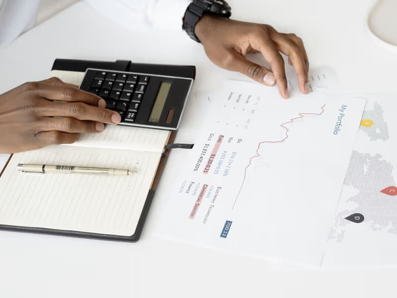 Hands with a calculator, notebook and documents on a desk