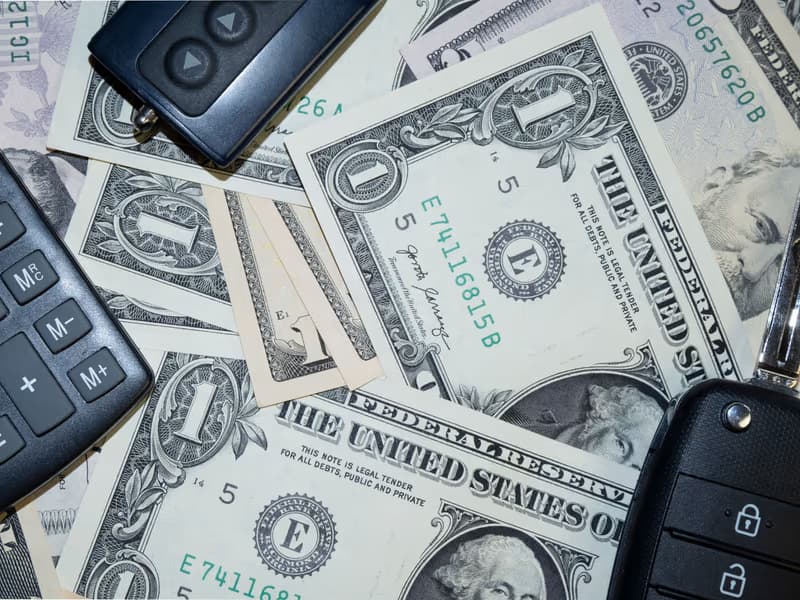 Car keys and a calculator on spread-out banknotes