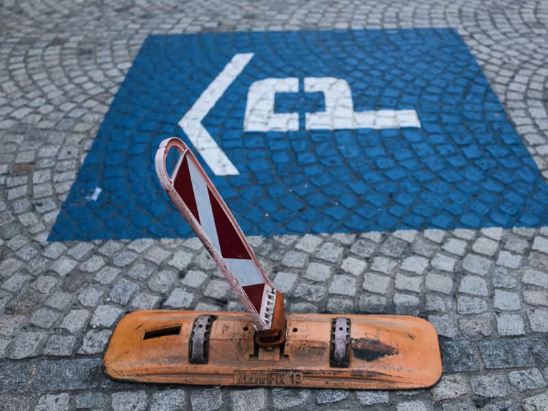 Disabled parking bay on cobblestones with a folding parking barrier