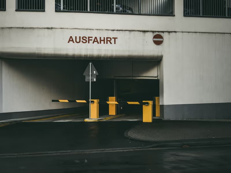 Car park exit marked ‘Ausfahrt’ with a raised barrier and no-entry sign